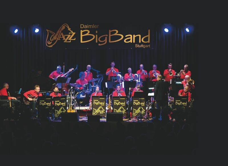 Die Daimler Jazz Big Band spielt auf einer Bühne in Stuttgart. Musiker in roten Hemden, Instrumente und Notenständer sind zu sehen., © Rosenau Kultur e.V. Die Daimler Jazz Big Band spielt auf einer Bühne in Stuttgart. Musiker in roten Hemden, Instrumente und Notenständer sind zu sehen., © Rosenau Kultur e.V.
