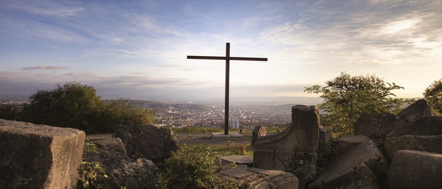 Mittig im Bild ist das gro&szlig;e Kreuz auf dem Birkenkopf zu sehen. Im Vordergrund liegen Tr&uuml;mmerhaufen. Im Hintergrund hat man eine Aussicht auf Stuttgart., &copy; Stuttgart-Marketing GmbH, Jean-Claude Winkler