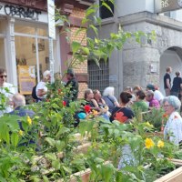 People are enjoying an urban garden in front of a building with the sign "Oberwelt." The atmosphere is relaxed., © Oberwelt e.V. People are enjoying an urban garden in front of a building with the sign "Oberwelt." The atmosphere is relaxed., © Oberwelt e.V.