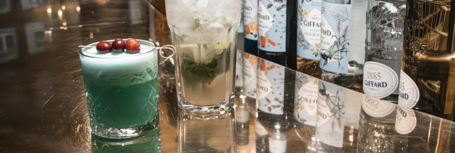 Two cocktails on a shiny bar. On the left a blue drink with berries, on the right a mojito. In the background are bottles of liqueurs., &copy; SMG Stuttgart Marketing GmbH - Sarah Schmid
