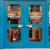 Large double door in bright blue with glass inserts on which "La Embajada Bar Lounge" is written in white letters., &copy; SMG Stuttgart Marketing GmbH - Sarah Schmid