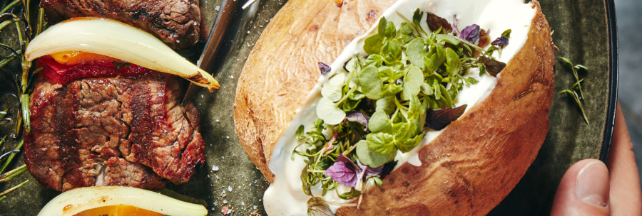 Grilled meat with peppers and onions, next to a baked potato with herbs and sour cream on a plate., &copy; MAREDO
