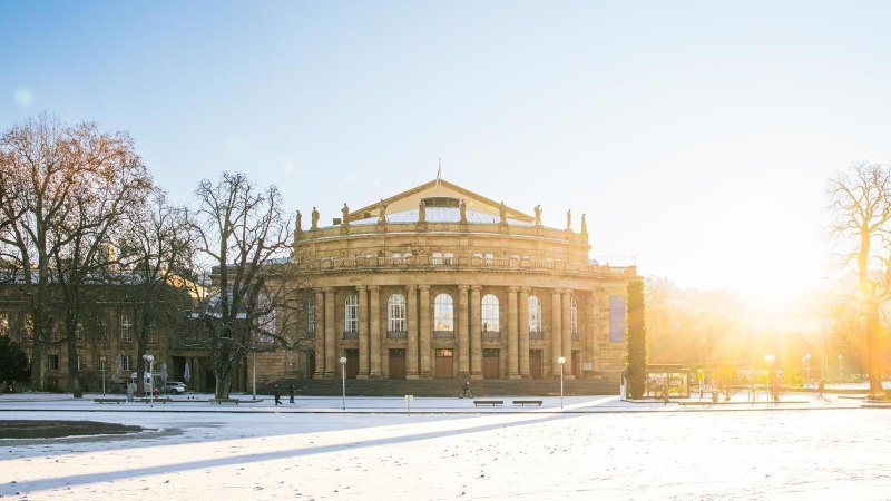 Die Stuttgarter Staatsoper im Winter, umgeben von schneebedecktem Boden und kahlen Bäumen. Die Sonne geht im Hintergrund auf und taucht die Szene in warmes Licht., © Stuttgart-Marketing GmbH, Sarah Schmid Die Stuttgarter Staatsoper im Winter, umgeben von schneebedecktem Boden und kahlen Bäumen. Die Sonne geht im Hintergrund auf und taucht die Szene in warmes Licht., © Stuttgart-Marketing GmbH, Sarah Schmid