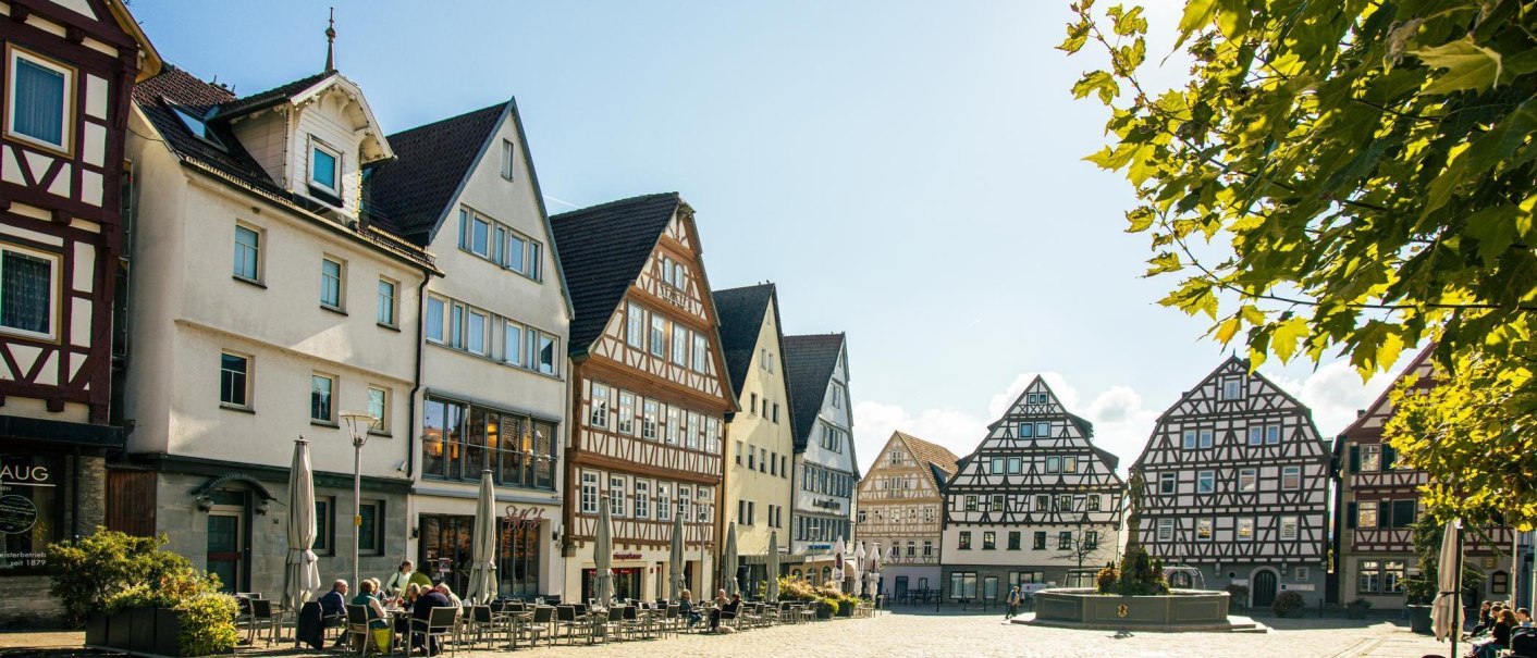Half-timbered houses in the old town of Leonberg. People sit at tables in a sunny square surrounded by historic buildings., © Stuttgart-Marketing GmbH, Sarah Schmid Half-timbered houses in the old town of Leonberg. People sit at tables in a sunny square surrounded by historic buildings., © Stuttgart-Marketing GmbH, Sarah Schmid