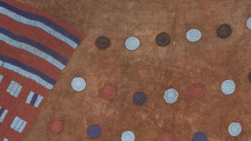 Detail eines Kunstwerks mit braunem Hintergrund, bunten Punkten und einem gestreiften Bereich links. Die Punkte sind in verschiedenen Farben angeordnet., &copy; Linden-Museum Stuttgart, Foto: Dominik Drasdow