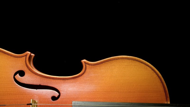 Nahaufnahme einer Violine mit sichtbarem f-Loch und Saiten, vor einem schwarzen Hintergrund., © Christian Steeneck Nahaufnahme einer Violine mit sichtbarem f-Loch und Saiten, vor einem schwarzen Hintergrund., © Christian Steeneck