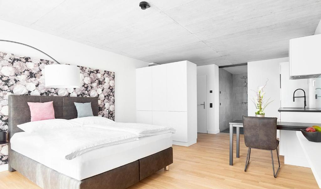 Modernes Zimmer mit Doppelbett, floralem Kopfteil, Schreibtisch, Stuhl und heller Einrichtung., © livisit bergapartments