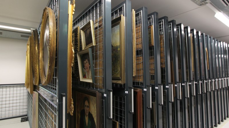 Ein Blick in einen Lagerraum mit Gem&auml;lden, die in verschiebbaren Metallregalen aufbewahrt werden. Die Bilder sind in verschiedenen Rahmen., &copy; Stadtarchiv Stuttgart; Foto: Susanne Kern