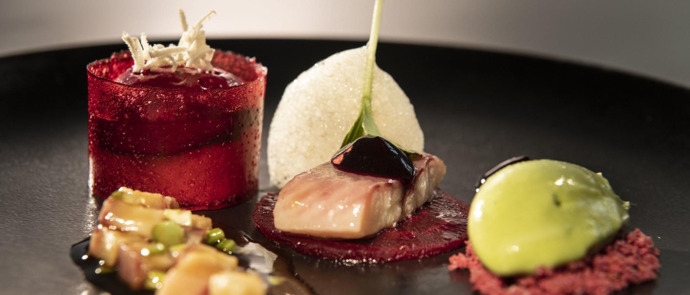 An artfully prepared gourmet dish with red jelly, fish and green cream on a black plate., &copy; Restaurant Bachofer