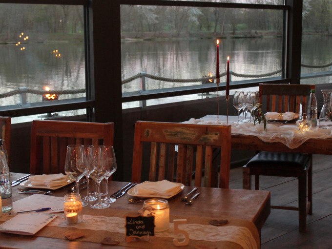 Ein romantisch gedeckter Tisch mit Kerzenlicht und Weingläsern, am Ufer eines Sees. Im Hintergrund ist die Abenddämmerung zu sehen., © Cool-Tours StattReisen Ein romantisch gedeckter Tisch mit Kerzenlicht und Weingläsern, am Ufer eines Sees. Im Hintergrund ist die Abenddämmerung zu sehen., © Cool-Tours StattReisen