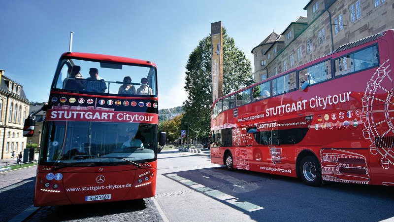 Zwei rote Doppeldeckerbusse der Stuttgart Citytour stehen vor dem Landesmuseum W&uuml;rttemberg. Menschen sitzen auf dem offenen Oberdeck., &copy; Stuttgart-Marketing GmbH, Pierre Polak