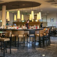 Moderne Bar mit runder Theke, Hängelampen und Sitzbereichen im Arcotel Camino. Menschen sitzen und genießen die Atmosphäre., © Harald Eisenberger Moderne Bar mit runder Theke, Hängelampen und Sitzbereichen im Arcotel Camino. Menschen sitzen und genießen die Atmosphäre., © Harald Eisenberger