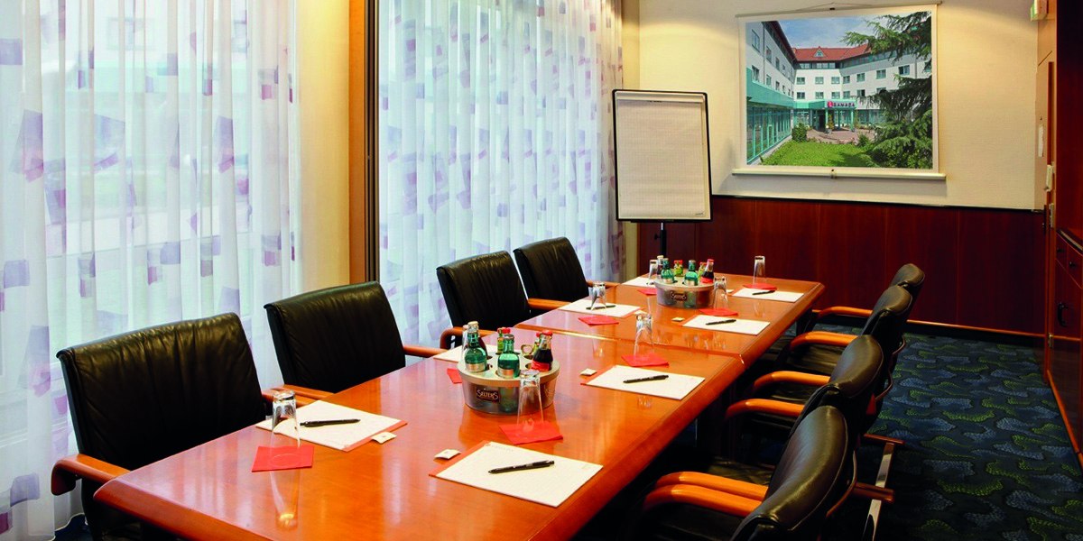 Seminar room with a long table, chairs, writing materials and drinks. There is a flipchart and a picture on the wall., © © H-Hotels.com Seminar room with a long table, chairs, writing materials and drinks. There is a flipchart and a picture on the wall., © © H-Hotels.com