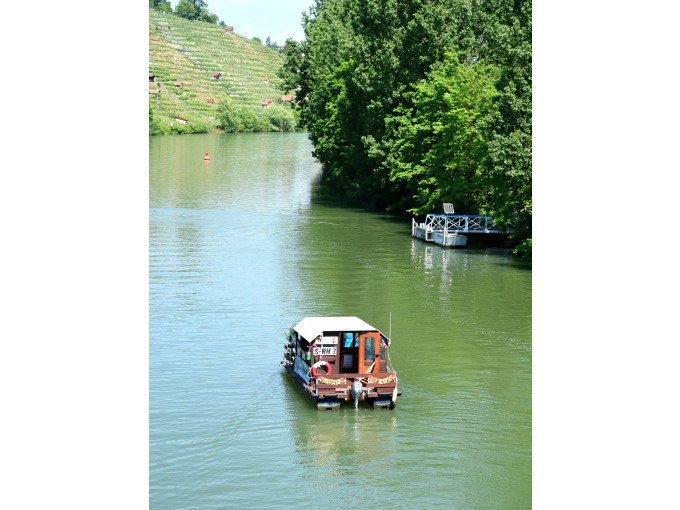 A raft boat on a river, surrounded by green trees and vineyards in the background., © Cool-Tours StattReisen A raft boat on a river, surrounded by green trees and vineyards in the background., © Cool-Tours StattReisen