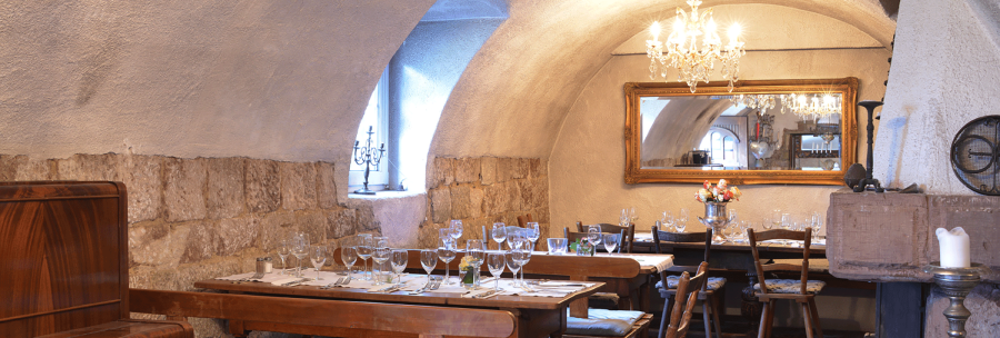 Cozy dining room with covered wooden tables, chandelier, mirror and rustic stone walls. Elegant atmosphere with candles and flowers., &copy; FreCla Gastronomiebetriebe GmbH