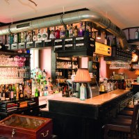 Bar mit Flaschen, Gläsern und Kupferdestille. Klosterfrau-Logo leuchtet im Hintergrund. Gemütliche Atmosphäre mit Holzmöbeln und Lampen., © Buschwerk Mediendesign-Wilhelmer Gastronomie Bar mit Flaschen, Gläsern und Kupferdestille. Klosterfrau-Logo leuchtet im Hintergrund. Gemütliche Atmosphäre mit Holzmöbeln und Lampen., © Buschwerk Mediendesign-Wilhelmer Gastronomie