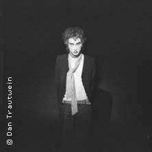 Eine Person mit lockigem Haar und Schal steht in einem dunklen Raum und blickt direkt in die Kamera. Das Bild ist in Schwarz-Weiß gehalten., © links im Bild Eine Person mit lockigem Haar und Schal steht in einem dunklen Raum und blickt direkt in die Kamera. Das Bild ist in Schwarz-Weiß gehalten., © links im Bild