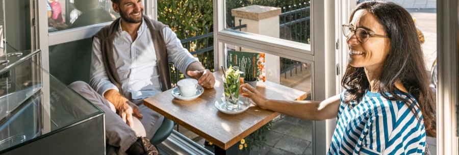 Zwei Personen sitzen in einem Café am Fenster, trinken Kaffee und unterhalten sich lächelnd. Sonnenlicht fällt durch das Fenster., © Stuttgart-Marketing GmbH, Sarah Schmid Zwei Personen sitzen in einem Café am Fenster, trinken Kaffee und unterhalten sich lächelnd. Sonnenlicht fällt durch das Fenster., © Stuttgart-Marketing GmbH, Sarah Schmid