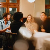 Four people are sitting in a cozy wine bar, chatting and enjoying wine. The atmosphere is warm and inviting., © © Stuttgart-Marketing GmbH, Alwin Maigler Four people are sitting in a cozy wine bar, chatting and enjoying wine. The atmosphere is warm and inviting., © © Stuttgart-Marketing GmbH, Alwin Maigler