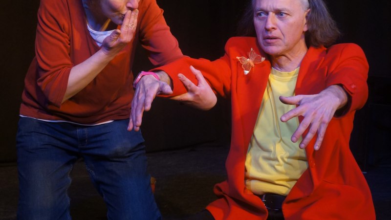 Zwei Personen auf einer B&uuml;hne, eine Frau und ein Mann, gestikulieren intensiv. Die Frau tr&auml;gt einen roten Pullover, der Mann ein rotes Sakko., &copy; kaba-reh prodcution