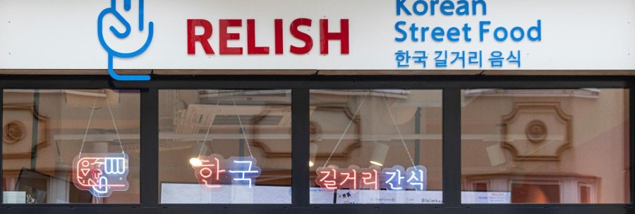 Entrance to a restaurant with the sign 'Relish Korean Street Food' and Korean characters. Neon lights in the window., &copy; Stuttgart-Marketing GmbH, Sarah Schmid