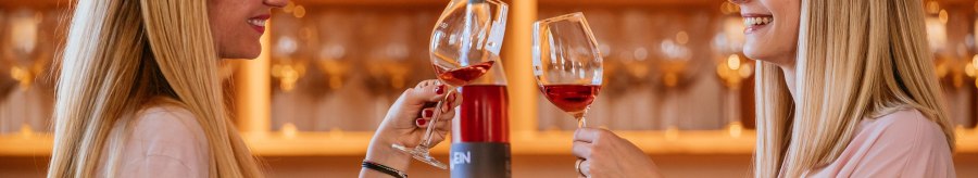 Zwei Frauen sto&szlig;en mit Weingl&auml;sern in einer Vinothek an. Im Hintergrund sind Weinflaschen und Gl&auml;ser zu sehen., &copy; Stuttgart-Marketing GmbH, Thomas Niederm&uuml;ller