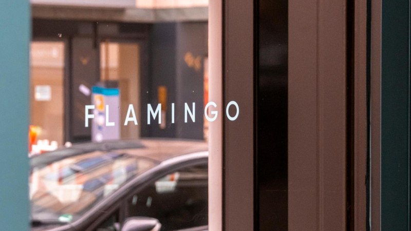 Weißer Schriftzug "FLAMINGO" in Großbuchstaben auf der verspiegelten Glasfront der Bar, © SMG, Sarah Schmid Weißer Schriftzug "FLAMINGO" in Großbuchstaben auf der verspiegelten Glasfront der Bar, © SMG, Sarah Schmid