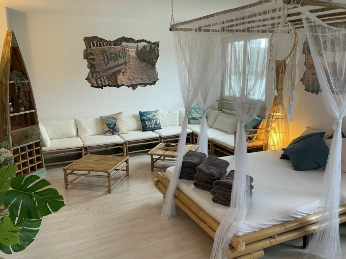 A cozy room with bamboo furniture, four-poster bed, sofas and beach decorations. Towels are laid out on the bed., © Cool-Tours StattReisen A cozy room with bamboo furniture, four-poster bed, sofas and beach decorations. Towels are laid out on the bed., © Cool-Tours StattReisen
