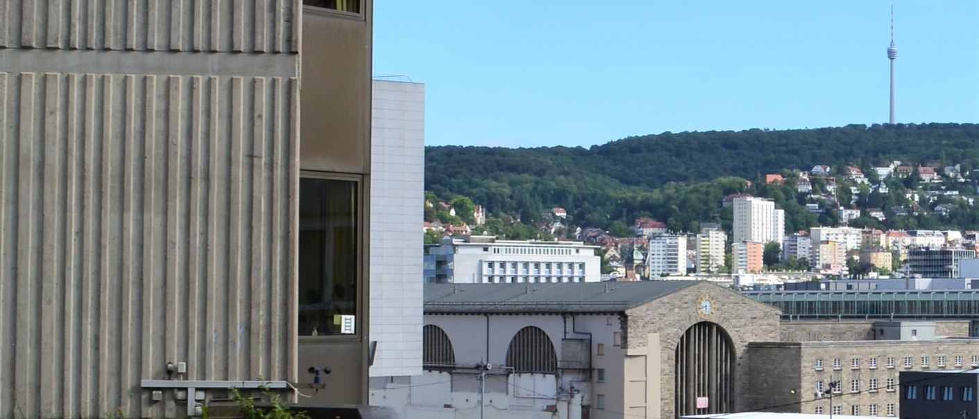 A cityscape with buildings, a crane, and a tower in the background. In the foreground is a green roof., © Hotel BaWü A cityscape with buildings, a crane, and a tower in the background. In the foreground is a green roof., © Hotel BaWü