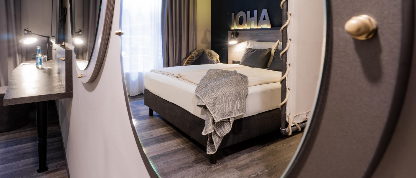 Modernes Hotelzimmer mit Doppelbett, Spiegel und Schreibtisch. Der Raum ist stilvoll dekoriert mit neutralen Farben und einem gro&szlig;en Fenster., &copy; HARBR. hotel Ludwigsburg / DQuadrat Living GmbH
