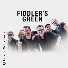Sechs Bandmitglieder von Fiddler's Green posieren lächelnd vor einem weißen Hintergrund. Oben steht der Schriftzug "Fiddler's Green"., © links im Bild