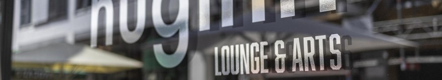 Reflection of the lettering 'huginn LOUNGE & ARTS' on a glass surface, blurred street scene in the background., &copy; SMG, Sarah Schmid