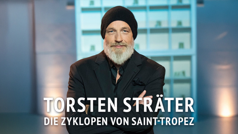 Ein Mann mit Bart und M&uuml;tze steht vor einem unscharfen Hintergrund. Text: Torsten Str&auml;ter - Die Zyklopen von Saint-Tropez., &copy; links im Bild