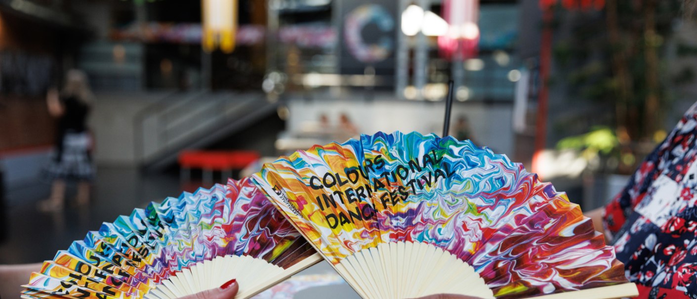 Colorful fans bearing the inscription “Colours International Dance Festival” are on display in the theater’s lobby., © Jeanette Bak Colorful fans bearing the inscription “Colours International Dance Festival” are on display in the theater’s lobby., © Jeanette Bak