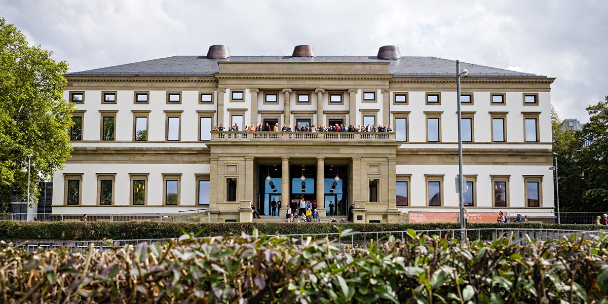 Das Stadtpalais – Museum für Stuttgart, ein klassizistisches Gebäude mit Menschen auf dem Balkon, umgeben von Bäumen und Hecken., © @ die arge lola / Kai Loges + Andreas Langen