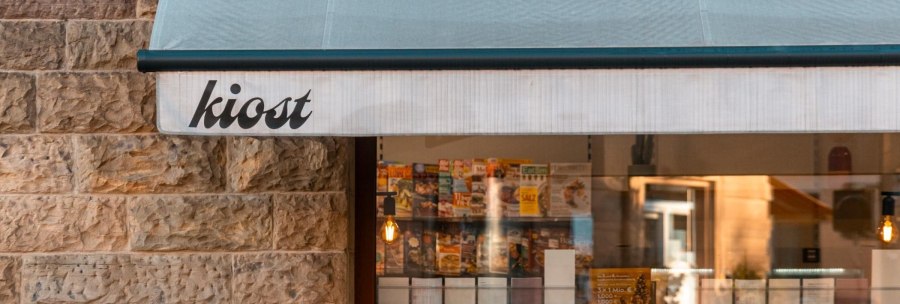A kiosk with the inscription 'kiost' displays magazines in the shop window. The stone wall and the light create a cozy atmosphere., © SMG Stuttgart Marketing GmbH - Sarah Schmid A kiosk with the inscription 'kiost' displays magazines in the shop window. The stone wall and the light create a cozy atmosphere., © SMG Stuttgart Marketing GmbH - Sarah Schmid