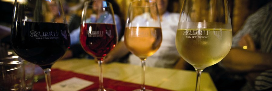 Four wine glasses with different types of wine stand on a table. People can be seen out of focus in the background., &copy; Stuttgart-Marketing GmbH