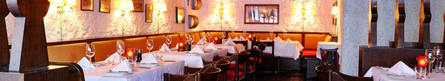 Cozy restaurant with wooden furniture, white tablecloths and warm lighting. The walls are rustic, decorated with pictures and lamps., © Steigenberger Graf Zeppelin