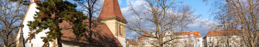 Der Uff-Kirchhof mit Kirche, Grabsteinen und Bäumen unter blauem Himmel; im Hintergrund stehen Wohnhäuser., © Peter Jagusch/Landeshauptstadt Stuttgart Der Uff-Kirchhof mit Kirche, Grabsteinen und Bäumen unter blauem Himmel; im Hintergrund stehen Wohnhäuser., © Peter Jagusch/Landeshauptstadt Stuttgart