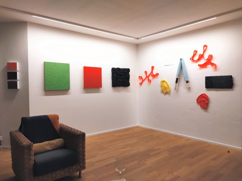 Galerieansicht mit moderner Kunst: Bunte Gemälde und Skulpturen an weißen Wänden, ein Sessel im Vordergrund., © galerie braun, stuttgart Galerieansicht mit moderner Kunst: Bunte Gemälde und Skulpturen an weißen Wänden, ein Sessel im Vordergrund., © galerie braun, stuttgart