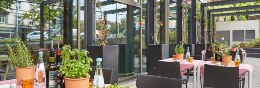 Restaurant terrace with red and white checkered tablecloths, herb pots and laid tables. Pasta and drinks are served., © Park Inn by Radisson Stuttgart Restaurant terrace with red and white checkered tablecloths, herb pots and laid tables. Pasta and drinks are served., © Park Inn by Radisson Stuttgart