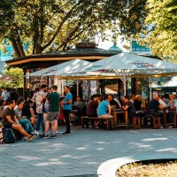 Belebter Biergarten mit vielen Menschen unter Sonnenschirmen, umgeben von Bäumen. Einige sitzen, andere stehen und unterhalten sich., © Stuttgart Marketing GmbH, Sarah Schmid