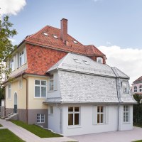 Two-storey house with red tiled roof, yellow façade and white windows, surrounded by trees and lawn., © Philip Kottlorz Two-storey house with red tiled roof, yellow façade and white windows, surrounded by trees and lawn., © Philip Kottlorz