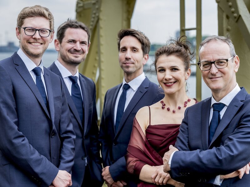 The Utopia Ensemble from Belgium poses in elegant clothing in front of a bridge construction. The group consists of four men and one woman., © Musik Podium Stuttgart e.V. The Utopia Ensemble from Belgium poses in elegant clothing in front of a bridge construction. The group consists of four men and one woman., © Musik Podium Stuttgart e.V.