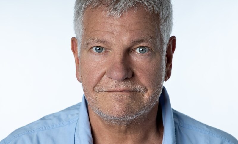 Ein &auml;lterer Mann mit grauen Haaren und Bart tr&auml;gt ein blaues Hemd. Er blickt direkt in die Kamera, der Hintergrund ist hell., &copy; Renitenztheater Stuttgart e.V.