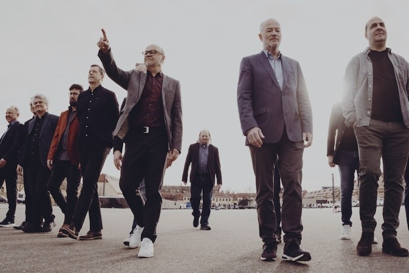 The SWR Big Band celebrates its 75th anniversary. A group of men in elegant clothing walk together across an open square., © SWR Big Band The SWR Big Band celebrates its 75th anniversary. A group of men in elegant clothing walk together across an open square., © SWR Big Band