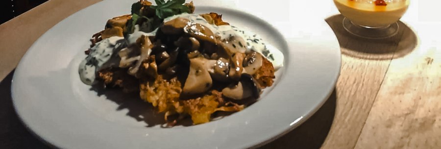 A plate with a dish and a dessert on a table, next to it a bucket of tulips. A painting of a woman in the background., &copy; Weinstube Fr&ouml;hlich Verwaltungs GmbH