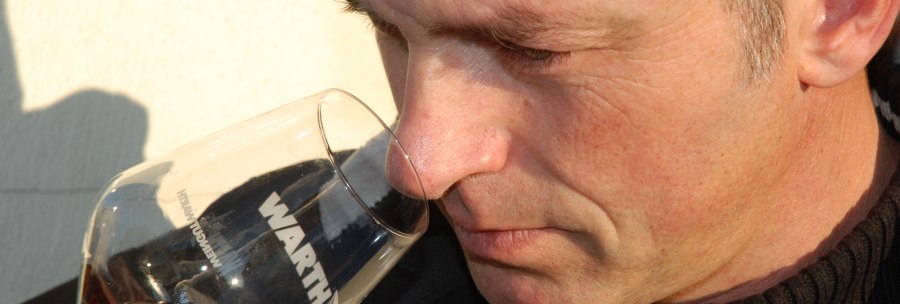A man smells a glass of red wine labeled 'WARTH' while enjoying the aromas., © Weingut Warth
