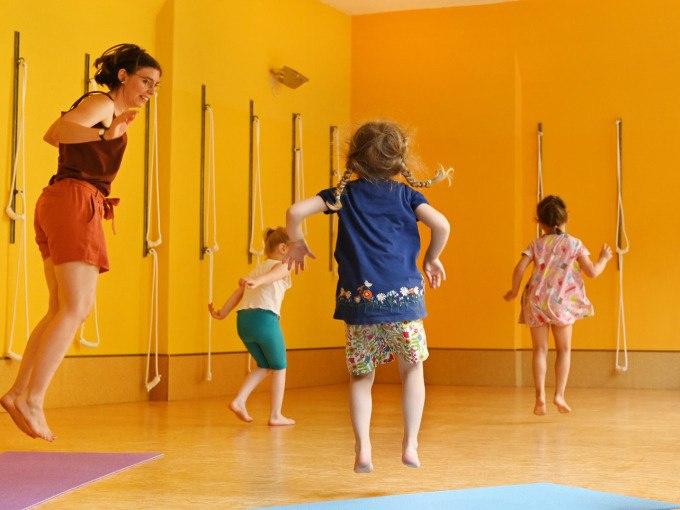 Children and an adult dance happily in a yellow room. The children are wearing colorful clothes and jumping in the air., &copy; Landesmuseum W&uuml;rttemberg