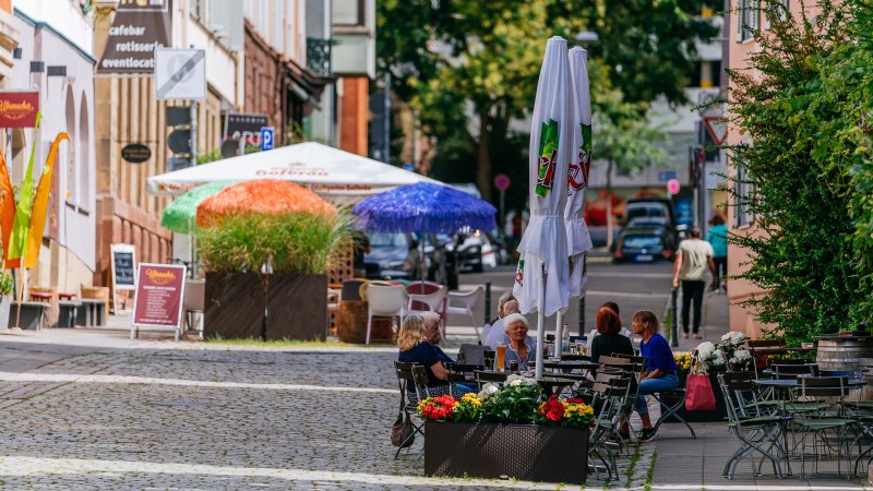 Gemütliche Straßenszene im Bohnenviertel mit Cafés, bunten Sonnenschirmen und Menschen, die im Freien sitzen. Pflastersteine und grüne Pflanzen säumen den Weg., © SMG Thomas Niedermüller Gemütliche Straßenszene im Bohnenviertel mit Cafés, bunten Sonnenschirmen und Menschen, die im Freien sitzen. Pflastersteine und grüne Pflanzen säumen den Weg., © SMG Thomas Niedermüller